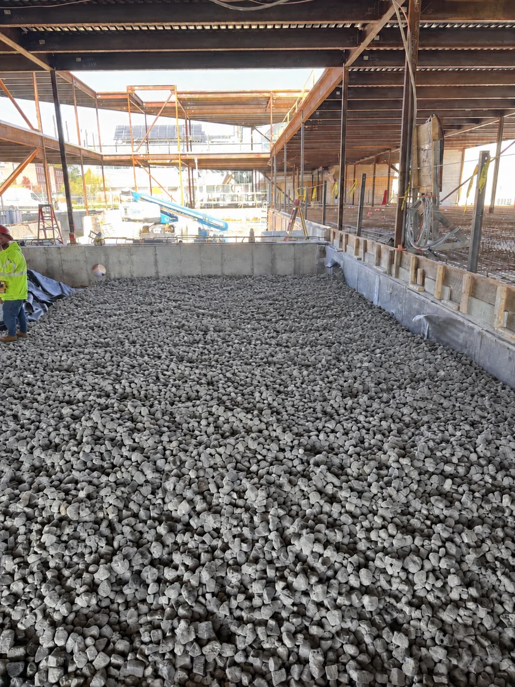 A worker standing on foam glass aggregate inside a building under construction
